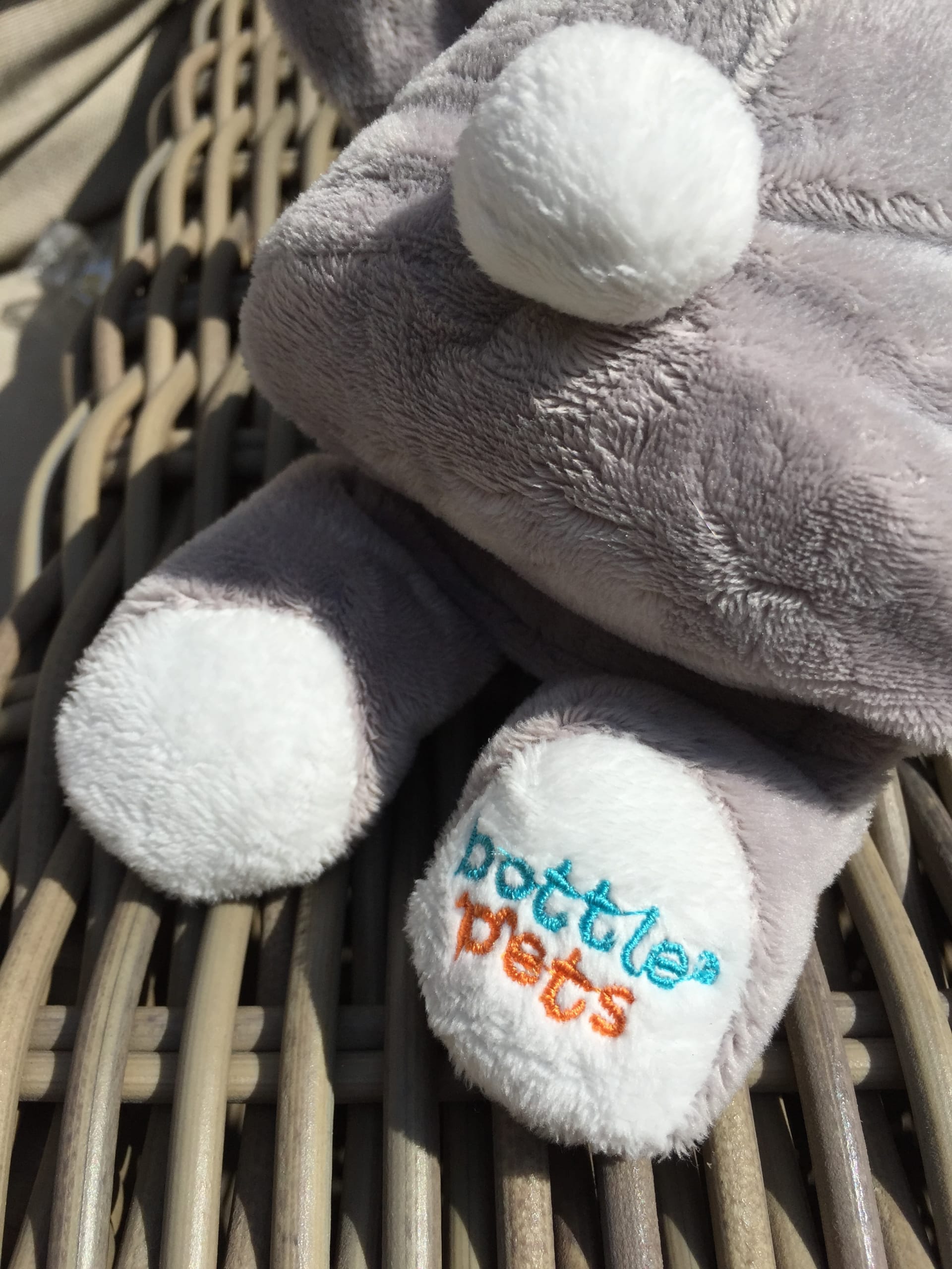 A Bottle Pet plushing with the logo embroidered on its foot.